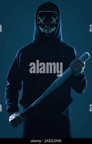 Porträt eines anonymen kriminellen Mann mit Baseballschläger in einer schwarzen Kapuze sein Gesicht hinter einer Maske. Studio gedreht. Stockfoto