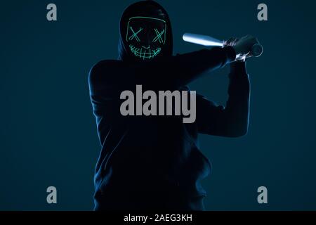 Porträt eines anonymen kriminellen Mann mit Baseballschläger in einer schwarzen Kapuze sein Gesicht hinter einer Maske. Studio gedreht. Stockfoto