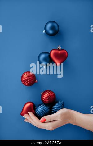 Weibliche Hand jonglieren Weihnachten runden Kugeln und Herzen Form flach Stockfoto