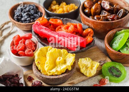 Vielzahl von getrockneten Früchten in Schalen. Datteln, Rosinen, getrocknete Aprikosen und exotische Getrocknete Ananas, Papaya und Kiwi, weisser Hintergrund. Stockfoto