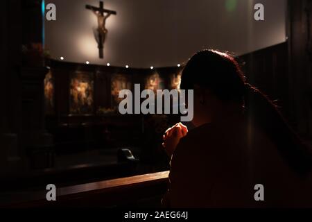 Deprimiert Frauen in der Kirche sitzen und beten zu Jesus am Kreuz, internationalen Tags der Menschenrechte Konzept Stockfoto