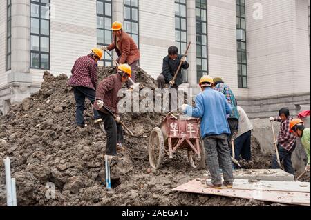 Weibliche WanderarbeiterInnen Schaufeln Erde auf Baustelle, Shanghai, China Stockfoto