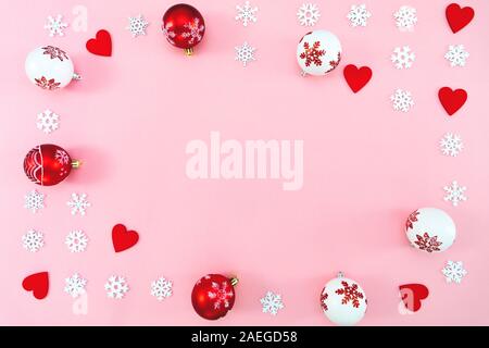 Weihnachten Komposition. Weihnachten Kugeln, rote Herzen und Schneeflocken Dekorationen auf rosa Hintergrund. Flach, Ansicht von oben, kopieren Raum Stockfoto