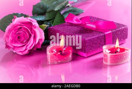 Valentinstag geschenk Box mit rosa Rose und brennende Kerzen auf eine reflektierende Tischplatte Stockfoto