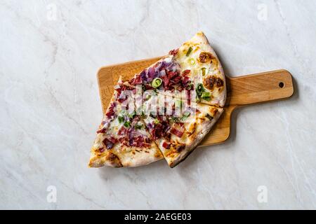 Flammkuchen, Pizza Scheiben/Traditionelle Tarte Flambee mit Creme Fraiche, Sahne, Käse, Speck und roten Zwiebeln auf Holzbrett. Traditionelle Fast Food. Stockfoto