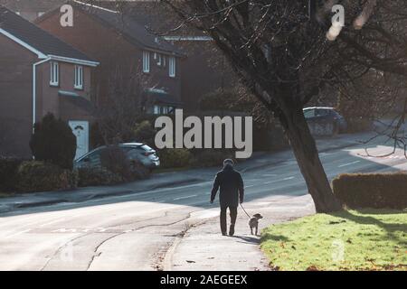 Ein Mann, der seinen Hund auf einem Winter sonniger Morgen in England Stockfoto