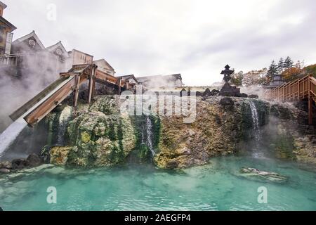 Weitwinkelansicht des fließenden schwefelhaltigen Wassers am Heißwasserfeld (Yubatake) im Kusatsu Onsen Thermalbad in Gunma, Japan, an einem bewölkten Tag. Stockfoto