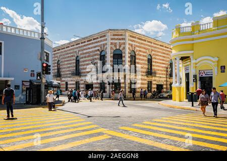 Merida, Yucatan, Mexiko: Menschen mit den farbigen Zebrastreifen durch hell gestrichenen Kolonialbauten in Merida Stadtzentrum umgeben. Stockfoto