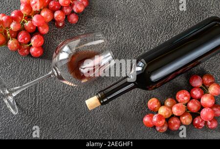 Glas und Flasche Rotwein mit Trauben: Ansicht von oben Stockfoto