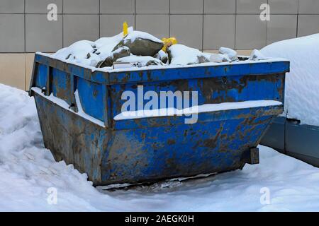 Blau industrielle Fracht Mülleimer in der Nähe der Baustelle gefüllt mit Müll. Von der Seite. Stockfoto