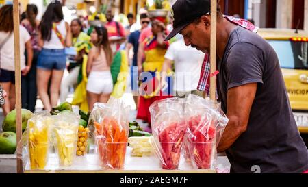Eine kolumbianische Mann verkaufen Obst auf den Straßen von Cartagena de Indias mit Menschen als unscharfer Hintergrund Stockfoto
