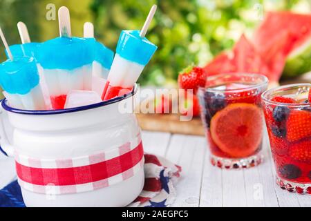 Hausgemachte rot-weiß-blauen Eis am Stiel auf einen Tisch im Freien mit erfrischenden Limonade im Hintergrund. Stockfoto