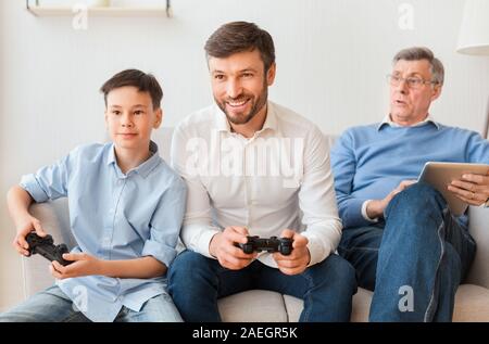 Mann spielt Videospiele mit Sohn und älteren Vati Indoor Stockfoto