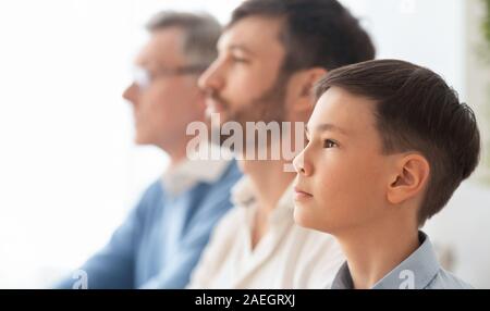 Portrait von Jungen, Vater und Großvater zu Hause, Side-View Sitzen Stockfoto