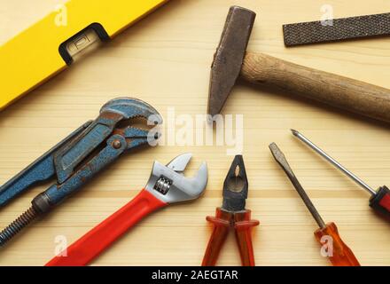 Die grundlegenden Werkzeuge für Do-it-your-Selfers wie Hammer oder Rohrzange verteilt auf einem hölzernen Hintergrund, Ansicht von oben Stockfoto