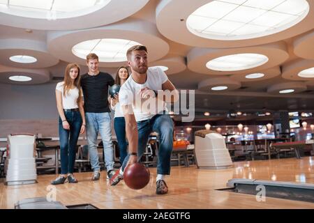 In der großen Halle. Junge fröhliche Freunde viel Spaß beim Bowling Club an den Wochenenden Stockfoto