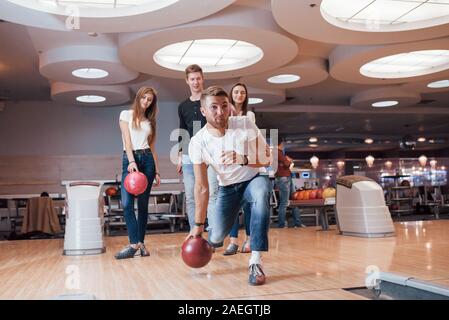 Genießen Sie das Spiel. Junge fröhliche Freunde viel Spaß beim Bowling Club an den Wochenenden Stockfoto