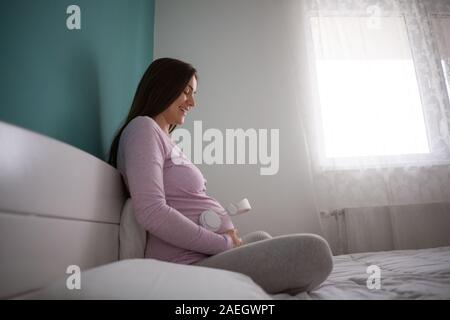 Gerne schwangere Frau Wiedergabe von Musik über Kopfhörer auf Ihr Baby. Stockfoto