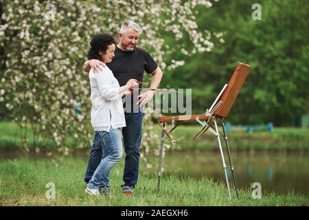 Ständigen in der Nähe des Sees. Reifes Paar haben Freizeitaktivitäten tagen und auf die Farbe gemeinsam im Park Stockfoto