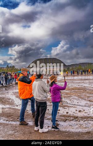 Menschen mit Regenschirm warten auf Strokkur Geysir, Eruption, Island Stockfoto