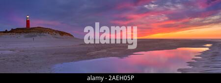 Der Leuchtturm von der Insel Texel in den Niederlanden bei Sonnenuntergang. Vom Strand unten, mit dem Sonnenuntergang Farben in eine Flutwelle po wider fotografiert. Stockfoto