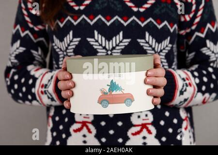 Frau in Urlaub Pullover mit Weihnachten Geschenk Box auf grauen Hintergrund, Ansicht schließen Stockfoto