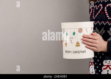 Frau in Urlaub Pullover mit Weihnachten Geschenk Box auf grauen Hintergrund, Ansicht schließen Stockfoto