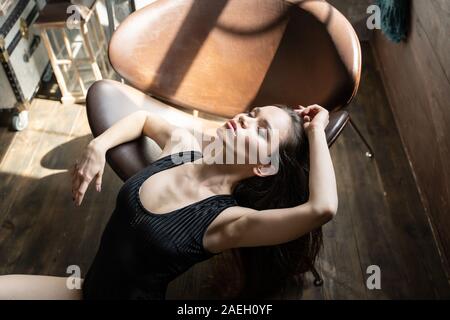 Portrait von Frau mit gesenktem Kopf auf Leder Stuhl Stockfoto