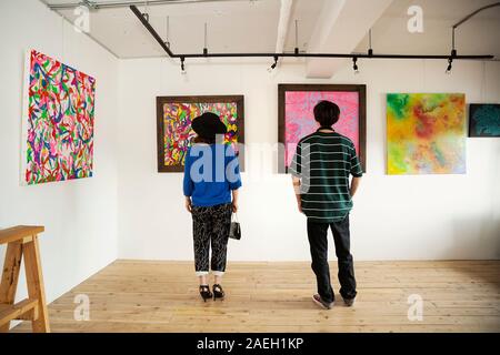 Ansicht der Rückseite des japanischen Mann und Frau an der Abstrakten Malerei in eine Kunstgalerie. Stockfoto
