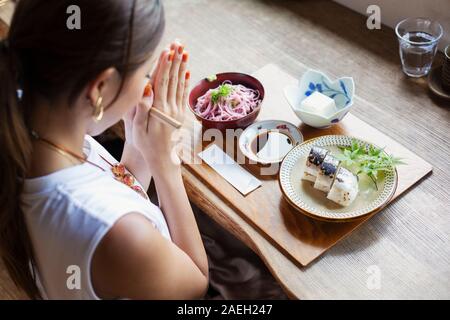 Hohe Betrachtungswinkel der japanischen Frau an einem Tisch sitzen in einem Japanischen Restaurant, Essen. Stockfoto
