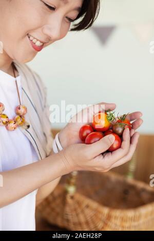 Hohen Winkel in der Nähe von japanischen Frau mit frisch gepflückten Tomaten. Stockfoto