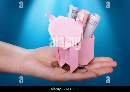 Piggy Bank suchen, um sich für die Münze mit Beleuchtung auf Blau Stockfoto
