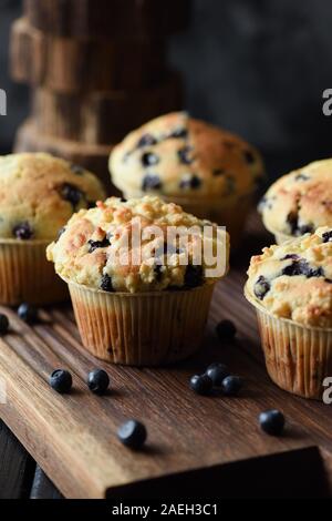 Hausgemachte bröckeln nach oben Blueberry Muffins mit Beeren auf Eiche Schneidebrett. Low Key noch Leben mit natürlichem Licht Seitenansicht Stockfoto