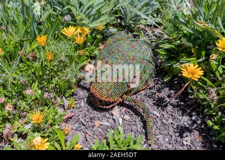 Dekorativer Frosch im Garten oder Blumenbeet im Park. Kreative Gartenarbeit. Stockfoto