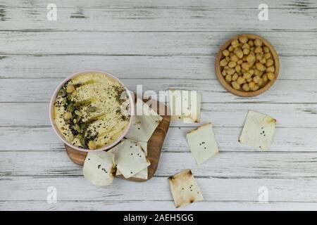 Hummus ist ein traditionelles Gericht der östlichen Küche in einem rosa Platte, auf weißem Hintergrund und Holzbrett. Hausgemachte von kichererbse, Sesampaste, Zitrone, d Stockfoto