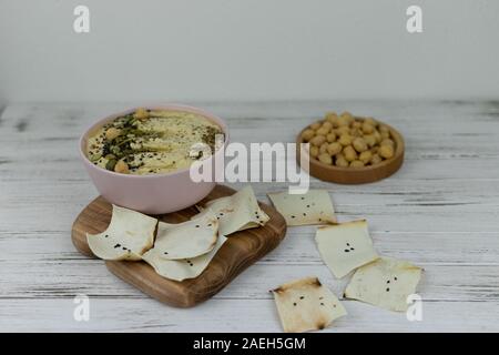 Hummus ist ein traditionelles Gericht der östlichen Küche in einem rosa Platte, auf weißem Hintergrund und Holzbrett. Hausgemachte von kichererbse, Sesampaste, Zitrone, d Stockfoto