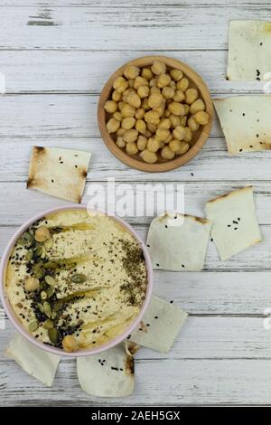 Hummus ist ein traditionelles Gericht der östlichen Küche in einem rosa Platte, auf einem weißen Holz- Hintergrund. Hausgemachte von kichererbse, Sesampaste, Zitrone, eingerichtet w Stockfoto