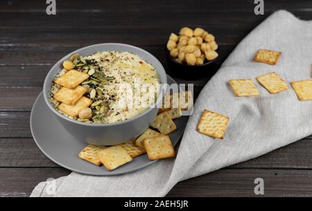 Hummus ist ein traditionelles Gericht der östlichen Küche in eine graue Platte, auf einem dunklen Hintergrund. Hausgemachte von kichererbse, Sesampaste, Zitrone, dekoriert wit Stockfoto