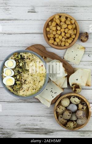 Hummus ist ein traditionelles Gericht der östlichen Küche in eine graue Platte, auf einem weißen Hintergrund aus Holz und Karton. Hausgemachte von kichererbse, Sesampaste, Zitrone Stockfoto