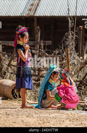 Drei junge Mädchen aus Kayan Stammes tragen traditionelle bunte Outfits spielen auf der Straße in der Pan Pet-Dorf. Stockfoto