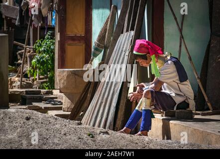 Eine ältere Frau aus Kayan Stammes, die traditionelle Outfit sitzen auf Ihrem Haus Veranda in Pan Pet-Dorf, Myanmar. Stockfoto