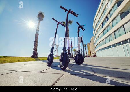 Drei schwarze Elektro-Roller für Erwachsene im Freien auf blauem Himmel tropischer Klima-Landschaft Hintergrund, keine Menschen. Moderne Technik Landfahrzeug Stockfoto