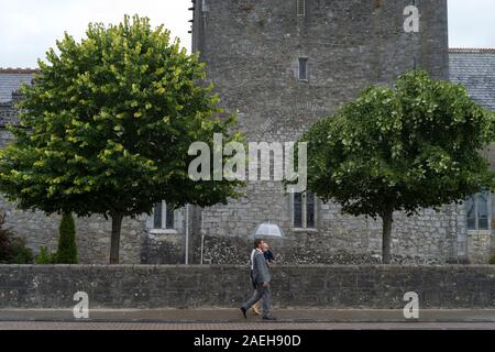 Paar mit ihrem Baby vor der Heiligen Dreifaltigkeit Abteikirche, Adare, County Limerick, Republik von Irland Stockfoto