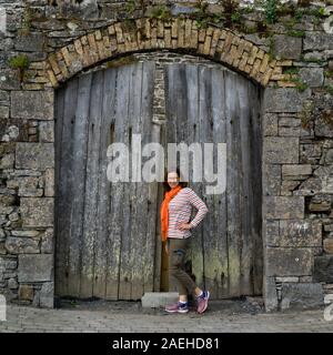 Frau, die gegen die alte Holztür in Killala Stadt, County Mayo, Irland Stockfoto