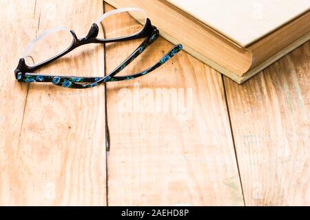 Altes Buch und Brille auf braunen Holzplanken Hintergrund Stockfoto