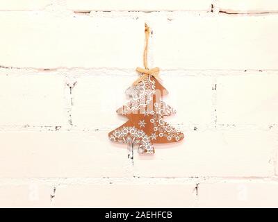 Weihnachten, kleiner Holzbaum. Die Dekorationen sind an der Wand in weiß befestigt und dienen als Dekoration im Inneren des Hauses. Stockfoto