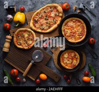 Gesund selbstgemachte vegetarische Kost. Rustikal frisch gebackene Pizza mit Pilzen und Tomaten mit rohen Zutaten auf dunklem Hintergrund der Ansicht von oben Stockfoto