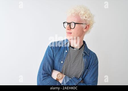 Junge albino blonder Mann tragen Jeanshemd und Gläser über isoliert weißer Hintergrund auf der Seite mit den Armen überzeugt und zuversichtlich gekreuzt Stockfoto