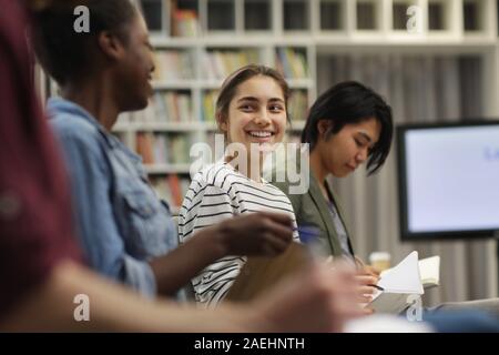 Junge Geschäftsfrau sitzen und Lächeln, während im Gespräch mit ihren Kollegen während eines Seminars Stockfoto