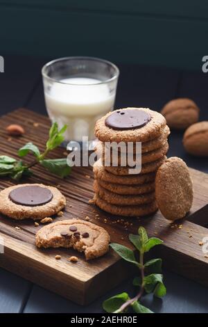 Gesunde vegane Spezialitäten. Peanut Butter und Mandeln biss Kekse mit Schokolade Tropfen serviert mit der Milch und Minze auf dunkelgrauem Hintergrund Stockfoto